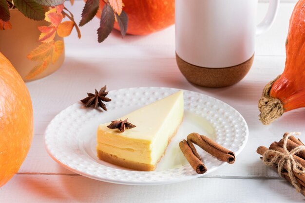 Jesienna kompozycja na Święto Dziękczynienia z kawałkiem ciasta dyniowego na białym talerzu i pomarańczowymi dyniami
