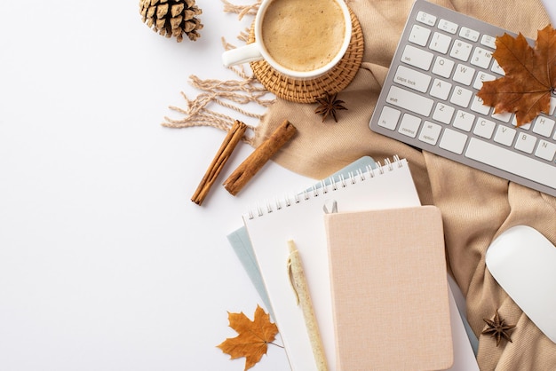 Jesienna koncepcja biznesowa widok z góry zdjęcie klawiatury myszy komputerowej filiżanka kawy na rattanowej podkładce przypomnienia laski cynamonu żółte liście klonu szyszka anyż i kratka na izolowanym białym tle