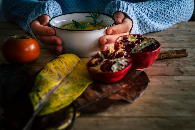 Jesienna koncepcja żywności i stylu życia z bliska kobieta ręce trzymając ciepłą zupę jarzynową na rustykalnym drewnianym stole ozdobionym żółtymi liśćmi Ludzie i zdrowy styl życia odżywianie dieta Jedzenie