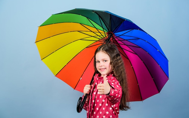Jesienna moda Mała dziewczynka w płaszczu przeciwdeszczowym Tęczowe wesołe hipsterskie dziecko w pozytywnym nastroju szczęśliwa mała dziewczynka z kolorowym parasolem Miejsce, w którym chcesz być