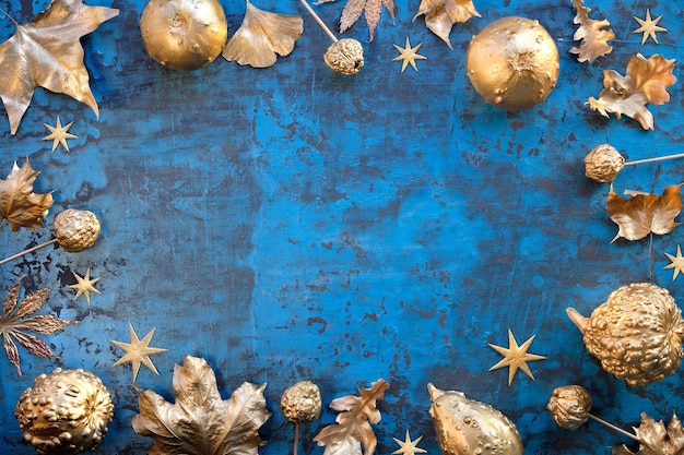 Jesienna ramka w klasycznym niebieskim i metalicznym złotym kolorze liści, dyni, owoców i gwiazd
