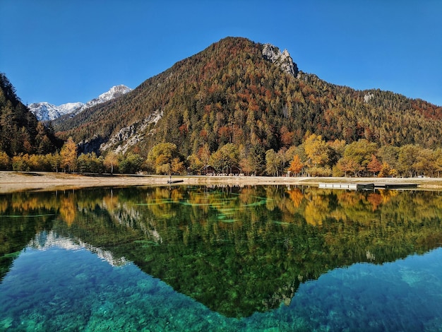 Zdjęcie jesienne alpy góry w świetle dziennym odbite w wodach zielonego jeziora jasna, kranjska gora. słowenia