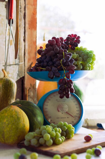 Jesienne martwa natura z dyniami, melonami, arbuzem, winogronami na skalę iw metalowej misce na drewnianym białym stole. Koncepcja zbiorów jesienią.