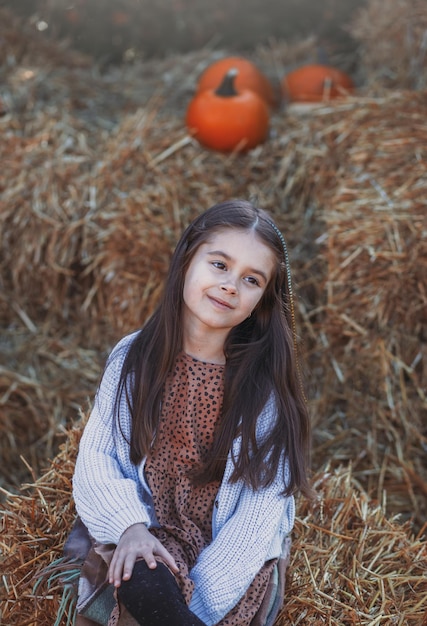 Jesienne zbiory dyni Dynia dziecięca i pomarańczowa na targu rolnym lub festiwalu sezonowym Słodka dziewczynka bawiąca się wśród dyń Święto Dziękczynienia i Halloween