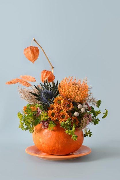 Jesienny bukiet z różnymi pomarańczowymi i żółtymi kwiatami w dyni na Święto Dziękczynienia