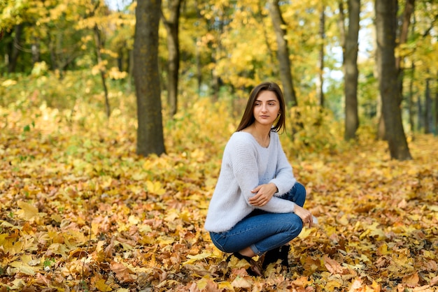 Jesienny krajobraz. Kobieta w stroju casual pozuje w parku z żółtymi liśćmi