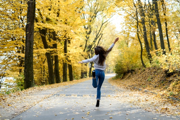 Jesienny krajobraz. Kobieta w stroju casual pozuje w parku z żółtymi liśćmi