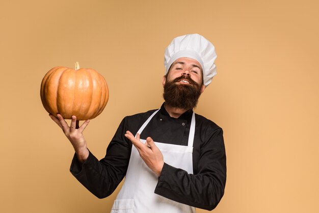Jesienny pomysł na jedzenie szef kuchni w białym fartuchu przedstawiający dynię na sezonowe kulinarne święto dziękczynienia