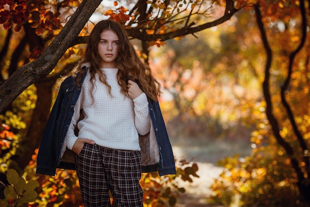 Jesienny portret szczęśliwej uroczej i pięknej kaukaskiej dziewczyny w lesie w jesiennych kolorach Koncepcja jesiennego nastroju
