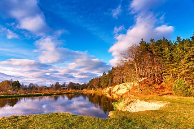 Jesieński krajobraz rzeki Zachód słońca Kolorowy las na brzegu rzeki Smoky na brzegu Piękna jesień Spokojna przyroda Białe chmury w listopadzie Głęboko niebieskie niebo Las na wzgórzu Europa Białoruś