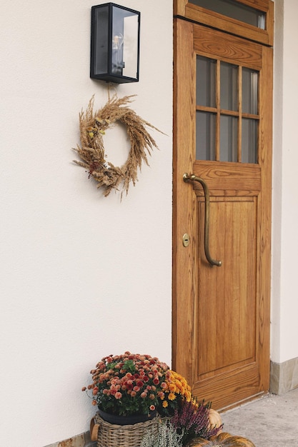 Jesieńskie wieńce dyni i garnki kwiatów przy drewnianych drzwiach przednich Stylowy jesienny dekor wejścia do gospodarstwa lub ganku