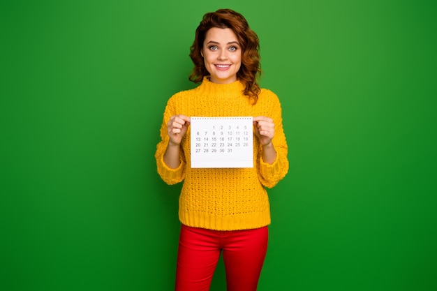 Jestem całkiem wolny! Zdjęcie całkiem wesołej pani trzymaj papierowy kalendarz pokazujący miesiąc bez planów nosić żółty sweter z dzianiny czerwone spodnie na białym tle zielony kolor ściany