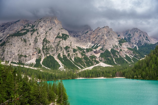 Zdjęcie jezioro braies otoczone lasami sosnowymi i skalistymi pasmami dolomitów w chmurne dni we włoszech