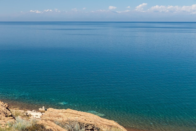 Jezioro issykkul kirgistan czysta woda w jeziorze i góry z ośnieżonymi szczytami w tle