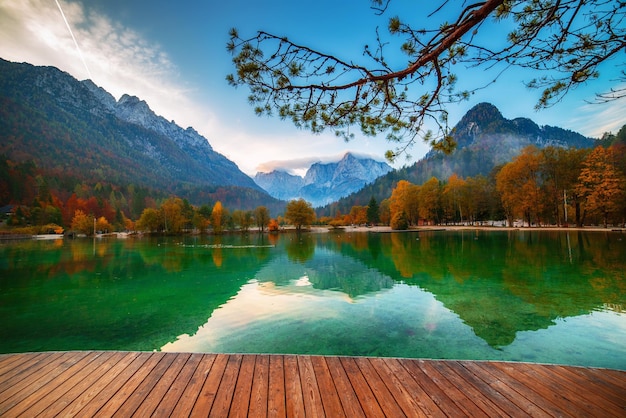 Jezioro Jasna z pięknymi refleksami gór i drewnianym molo. Park Narodowy Triglav, Słowenia