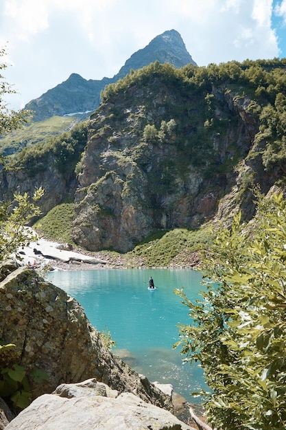 Jezioro w górach skały i kamienie odbicie nieba i chmur w wodzie alpejskie łąki i lasy na zboczu góry