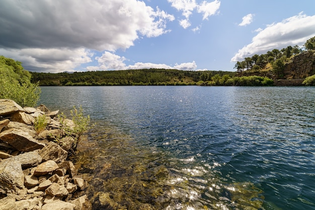 Jezioro z chmurami, niebieskim niebem i odbiciami w wodzie. Atazar Reservoir Madryt, Hiszpania,