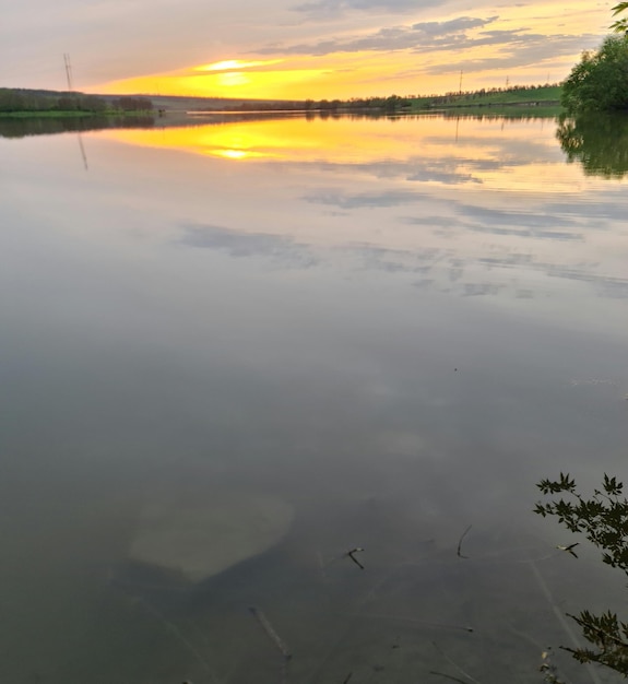 Jezioro z zachodem słońca i kilkoma chmurami na niebie