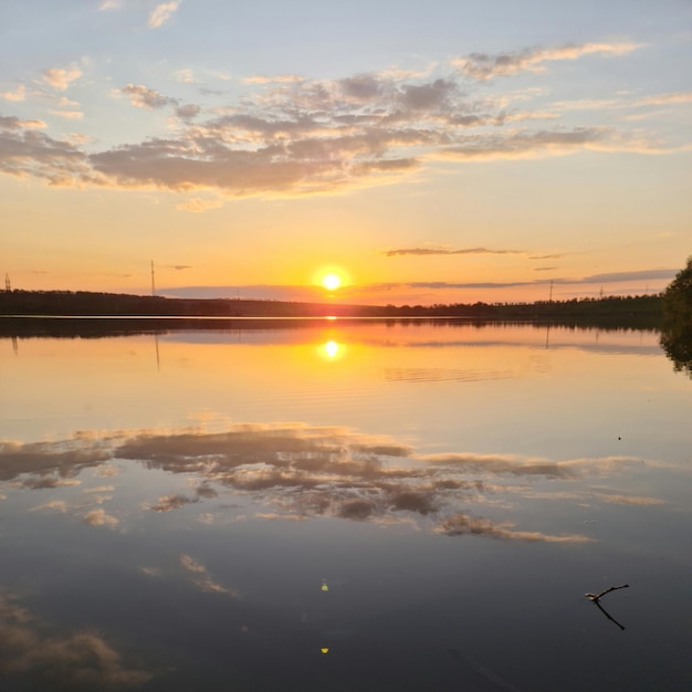 Jezioro z zachodem słońca i odbiciem nieba i chmur.