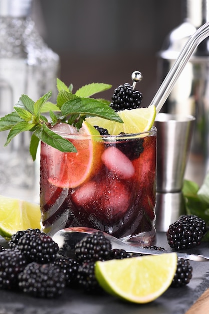 Jeżynowy letni koktajl mojito. Zimny orzeźwiający organiczny napój alkoholowy z jagodami, limonką, miętą