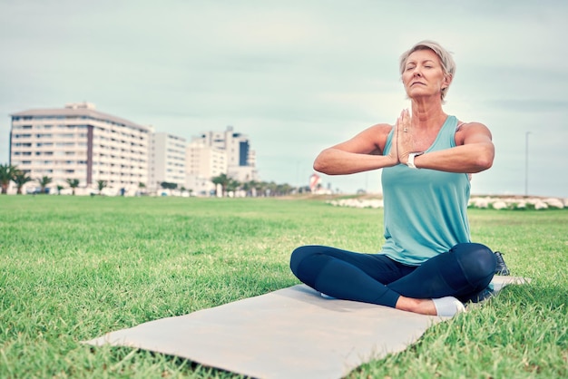 Joga medytacja starsza kobieta i fitness na świeżym powietrzu dla pilates wellness zdrowie psychiczne lub ćwiczenia na makiecie nieba Starsza pani medytuje w parku, aby zrelaksować się w celu uzdrawiania pokoju lub rąk zen namaste