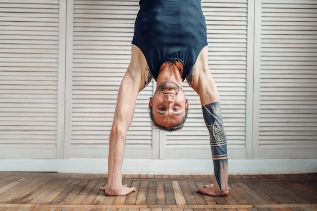 Zdjęcie joga stojąc na rękach, ćwiczenia do góry nogami. mężczyzna sportowiec na treningu fitness w pomieszczeniu