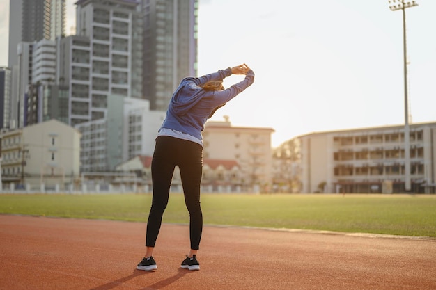 Jogging, fitness, bieganie, ćwiczenia, styl życia, zdrowa koncepcja. Młode kobiety rozgrzewają ciało po bieganiu na bieżni wokół boiska piłkarskiego.