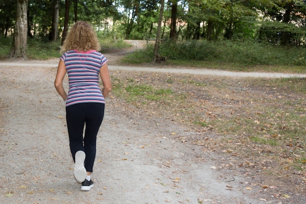 Jogging kobieta działa w parku w słońcu na piękne lato