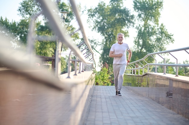 Jogging. Mężczyzna W Białej Odzieży Sportowej Biegający W Parku