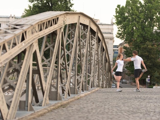 jogging para rozgrzewa się i rozciąga przed porannym treningiem biegowym w mieście ze wschodem słońca w tle