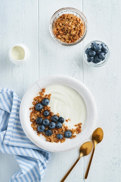 Jogurt jogurt grecki z muesli i świeżych jagód w białej misce na starym białym tle drewna Koncepcja rano śniadanie Zdrowe jedzenie na śniadanie widok z góry