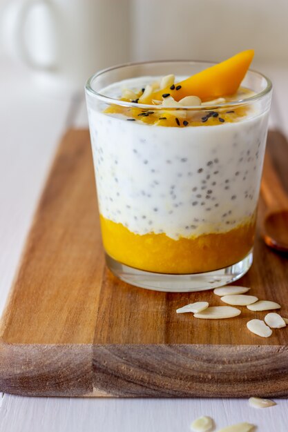 Jogurt w szklance z mango, chia i migdałami. Zdrowe odżywianie. Jedzenie wegetariańskie. Przepis. Śniadanie. Dieta.