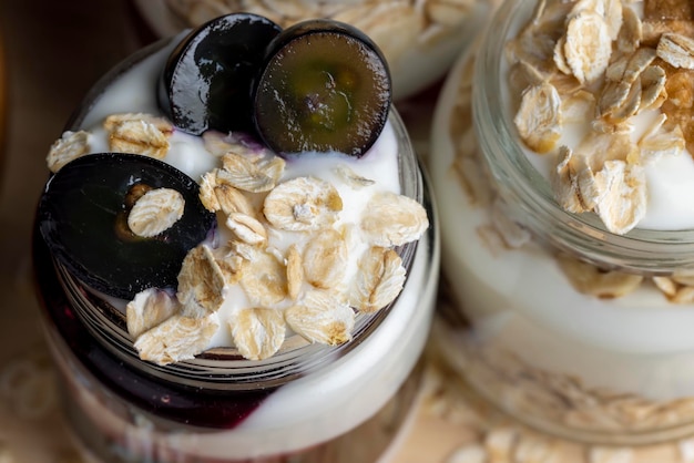 Zdjęcie jogurt w szklanym słoiczku z dodatkiem musli i winogron słodki jogurt o smaku winogronowym