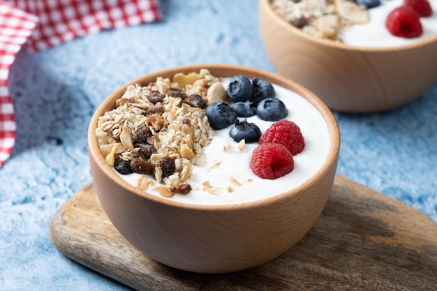 Jogurt z jagodami i muesli na śniadanie w misce na niebieskim tle