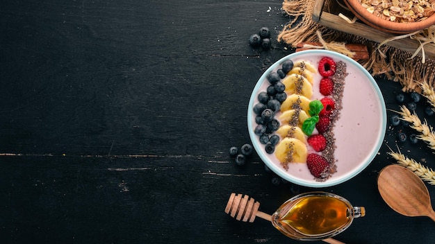 Jogurt z jagodami, malinami i bananem W talerzu Na drewnianym tle Widok z góry Wolne miejsce na tekst