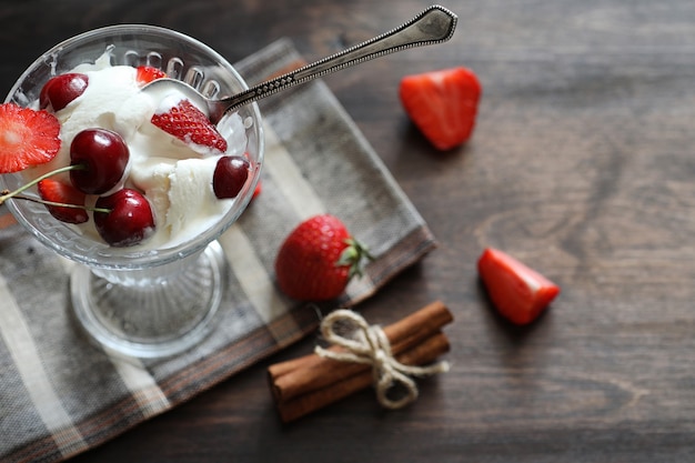 Jogurt ze świeżymi soczystymi truskawkami i wiśniami na drewnianym stole