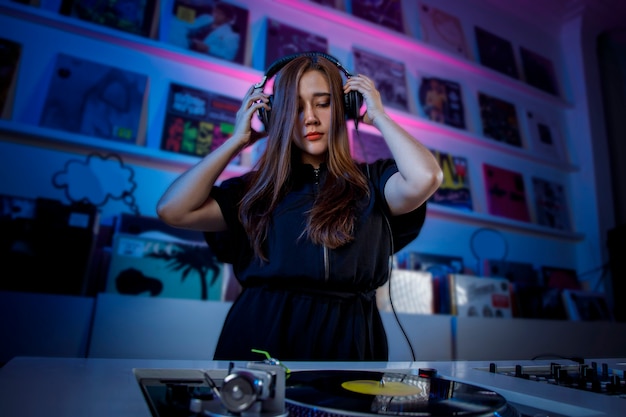 Joven mujer dj latina mezclando musica en una tienda de discos de vinilo