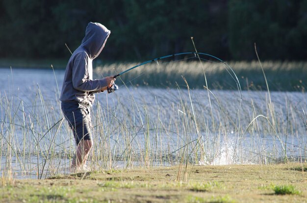 joven pescando con la cana curva por el pique en un lago de la patagonia