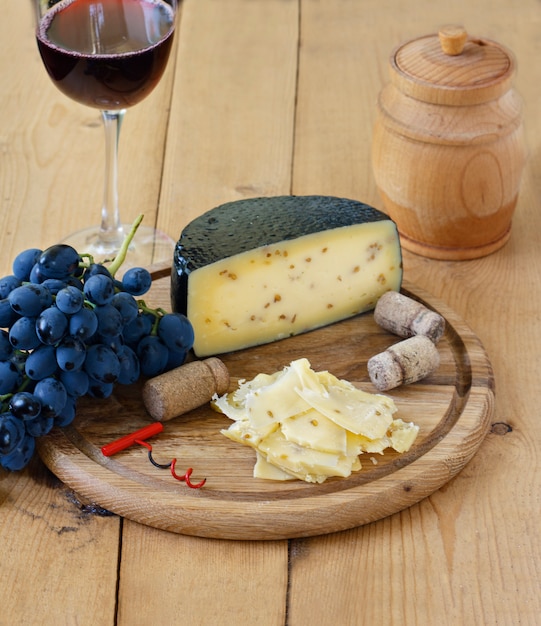 Kachota ser na drewnianej desce na drewnianym tle z winem w szkle