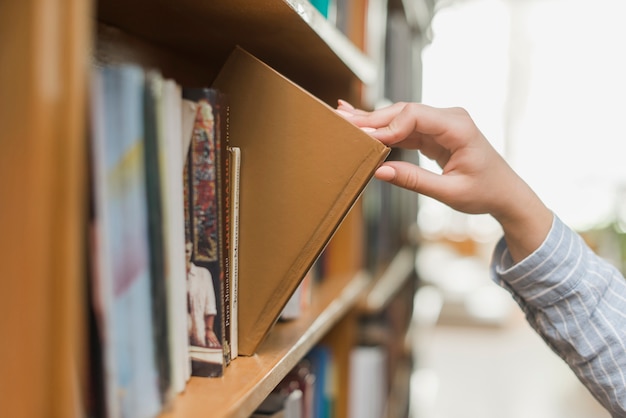 Zdjęcie kadrowa ręka bierze książkę od bookcase