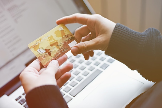 Kadrowanie z góry kobiety trzymającej kartę kredytową podczas zakupów online za pomocą laptopa