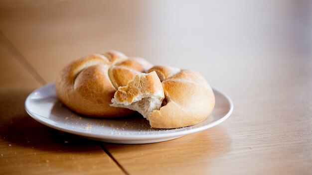 Kaiser roll na talerzu na drewnianym stole, widok z boku