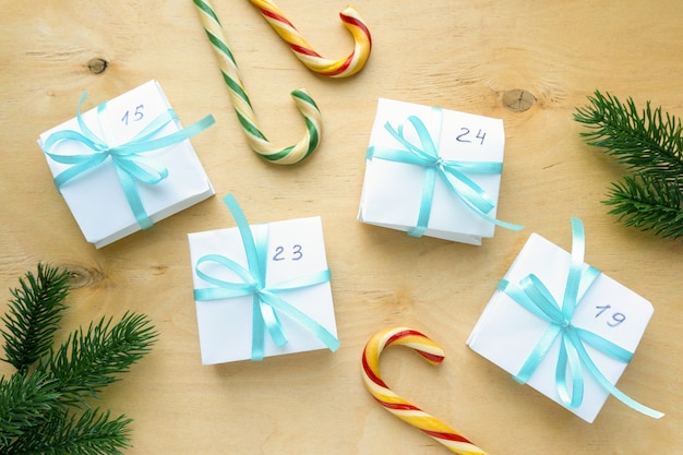 Kalendarz adwentowy na Boże Narodzenie. Domowe pudełka na prezenty z niebieską wstążką na drewnianym tle, widok z góry