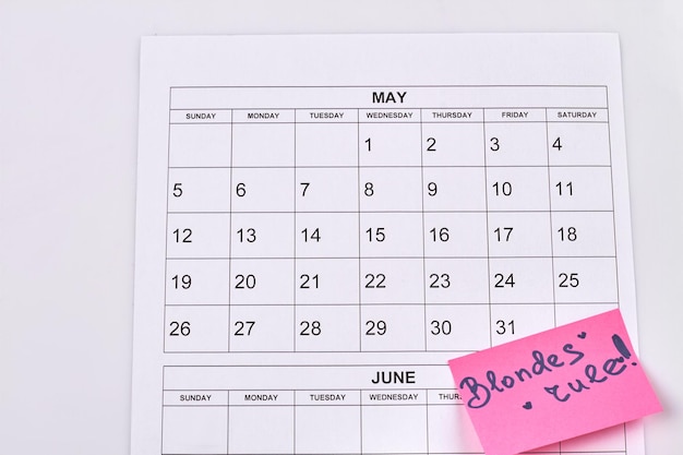 Zdjęcie kalendarz koncepcja dzień blondynki na białym tle blond zasady na różowej naklejce