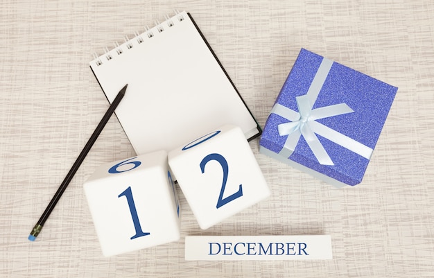 Kalendarz kostki na 12 grudnia i pudełko upominkowe, w pobliżu notesu z ołówkiem