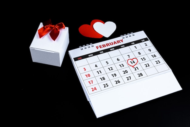 Kalendarz z czerwoną ręką napisany podkreśla serca 14 lutego Saint Walentynki