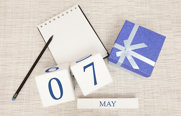 Zdjęcie kalendarz z modnym niebieskim tekstem i cyframi na 7 maja oraz prezentem w pudełku.