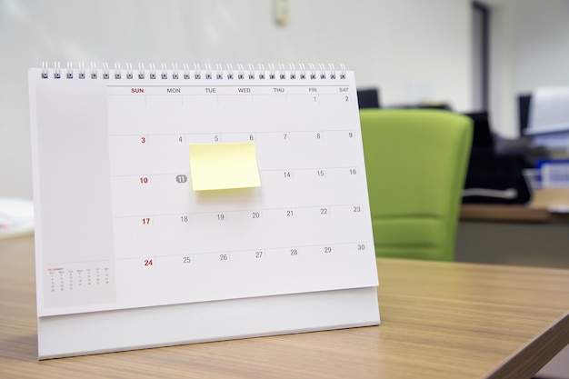 Kalendarz z notatką w formie papierowej na biurku dla planisty wydarzeń jest zajęty lub planuje