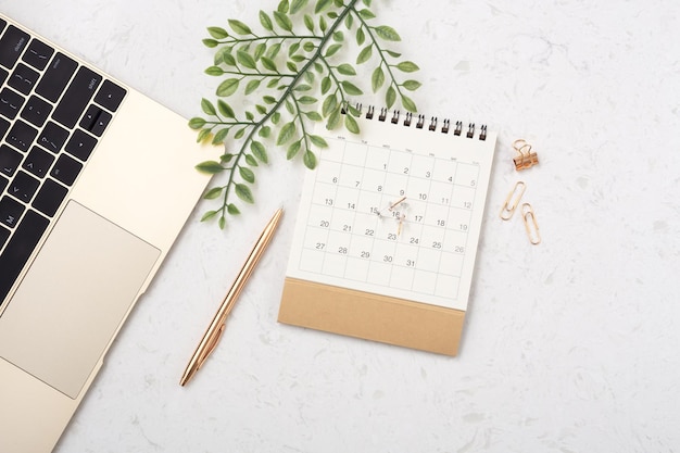 Kalendarz ze złotym długopisem i zielonym liściem