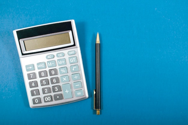 Kalkulator i długopis na niebieskim tle